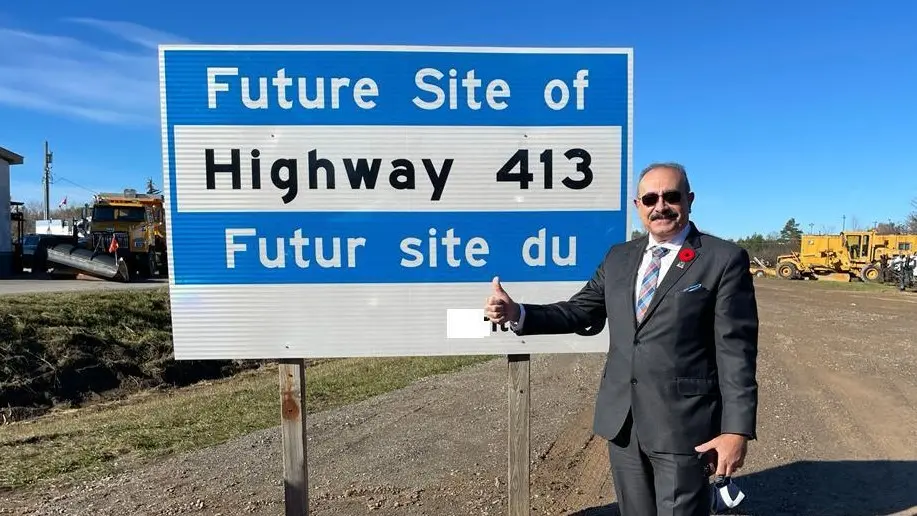 MPP Sheref Sabawy gives a thumbs up beside a sign that reads "Future Site of Highway 413"